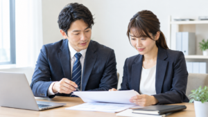 静かなオフィスで書類を確認するビジネスパーソンの男女